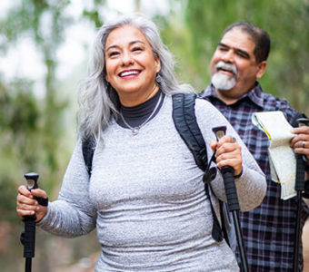 Couple walking on a trail outdoors using walking poles