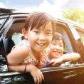 Father and children smiling while looking out car windows