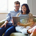 Couple sitting on couch looking at digital tablet together