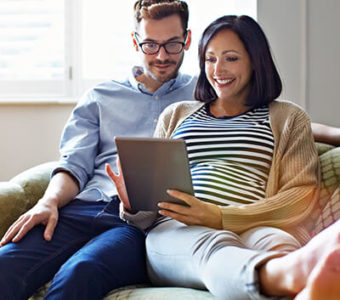 Couple sitting on couch looking at digital tablet together