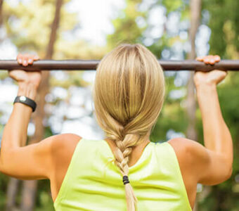 Woman doing pull-ups on an outdoor metal bar