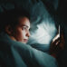 Person in bed lying awake and looking at phone