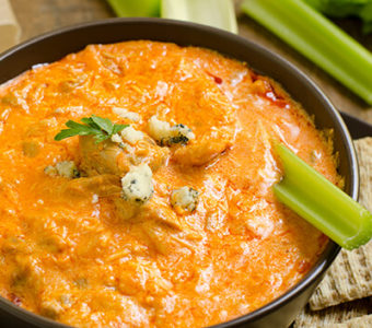 Bowl of buffalo chicken dip with celery sticks and crackers