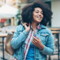 Woman smiling and standing outside while holding handbag