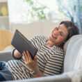 Woman laughing while looking at her digital tablet