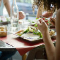 Closeup of a group of people dining together with meals on plates in front of them