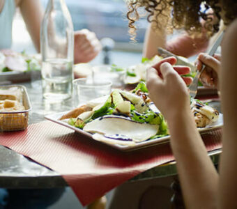 Closeup of a group of people dining together with meals on plates in front of them