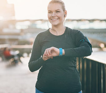 Smiling woman checking smart watch while walking along riverfront