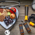 Heart shaped plate with grains, fruits and vegetables sitting next too workout equipment and a stethoscope