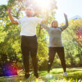 Mother and daughter doing jumping jacks and exercising outside in sun