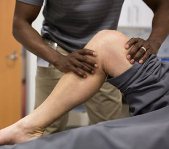 Physical therapist assessing a person's injury in their knee