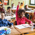 School children in class with their hands raised