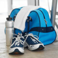 Closeup of gym shoes sitting in front of a gym bag, towel and water bottle