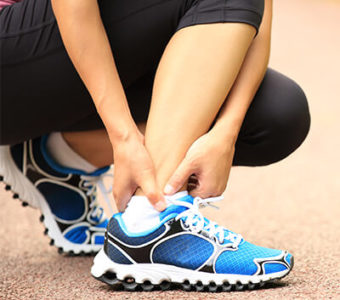 Closeup of person holding ankle bottom of leg in pain