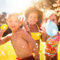 Group of children wearing swimsuits throwing water balloons