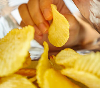 Closeup inside of potato chip bag as a hand pulls out a potato chip