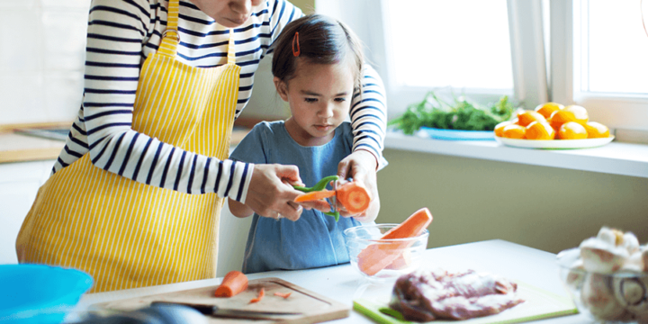 Adult and child peeling carrots at a kitchen countertop