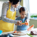 Adult and child peeling carrots at a kitchen countertop