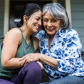 Older woman hugging adult daughter on house porch