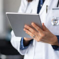 Close up of doctor with stethoscope holding a tablet