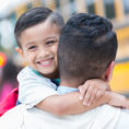 Father holding son on his way to the school bus